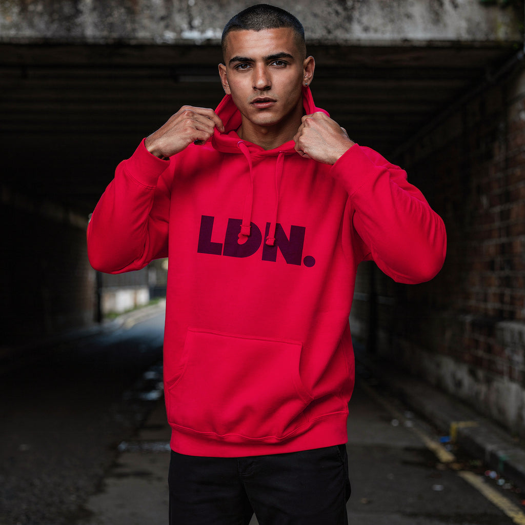 Unisex Hoodie - Red hoodie with tonal “LDN.” graphic worn by male model — soft fleece lining, relaxed streetwear silhouette, perfect for layering in cooler seasons.