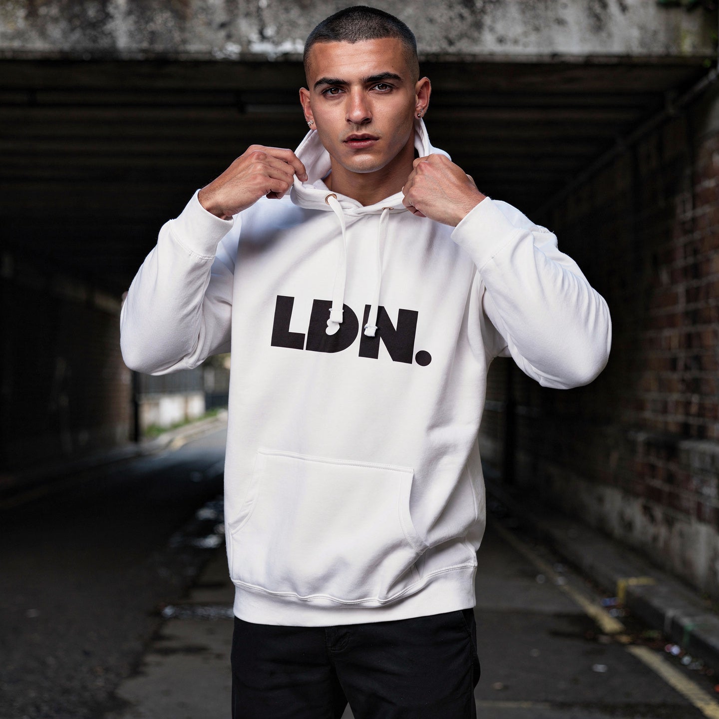 Unisex Hoodie - White hoodie with tonal “LDN.” graphic worn by male model — soft fleece lining, relaxed streetwear silhouette, perfect for layering in cooler seasons.