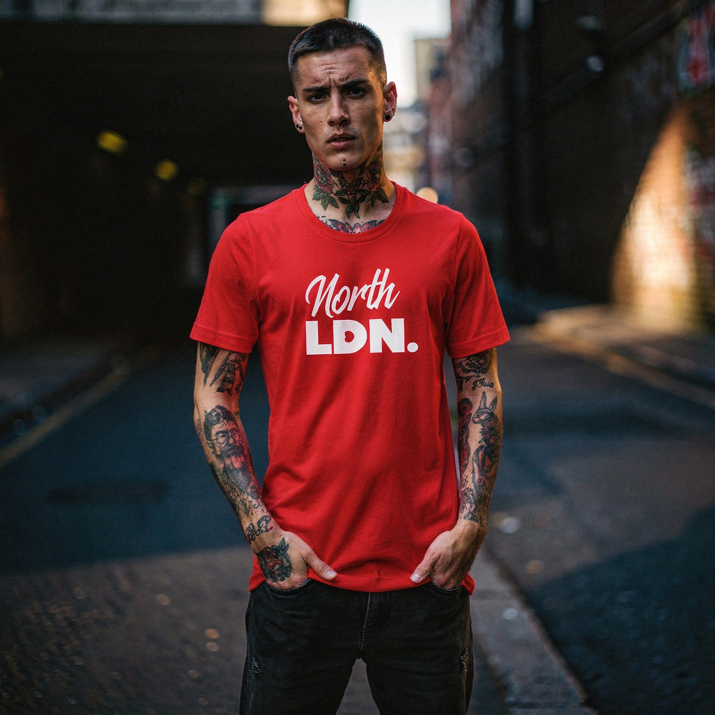 Man wearing a red 'North LDN' t-shirt standing on a street.