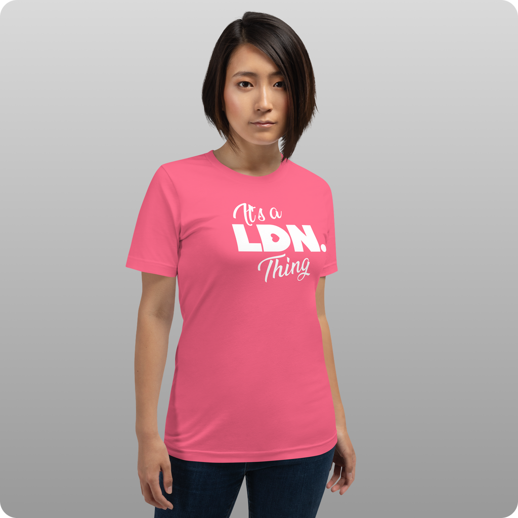 Person wearing a pink t-shirt with text on a gray background
