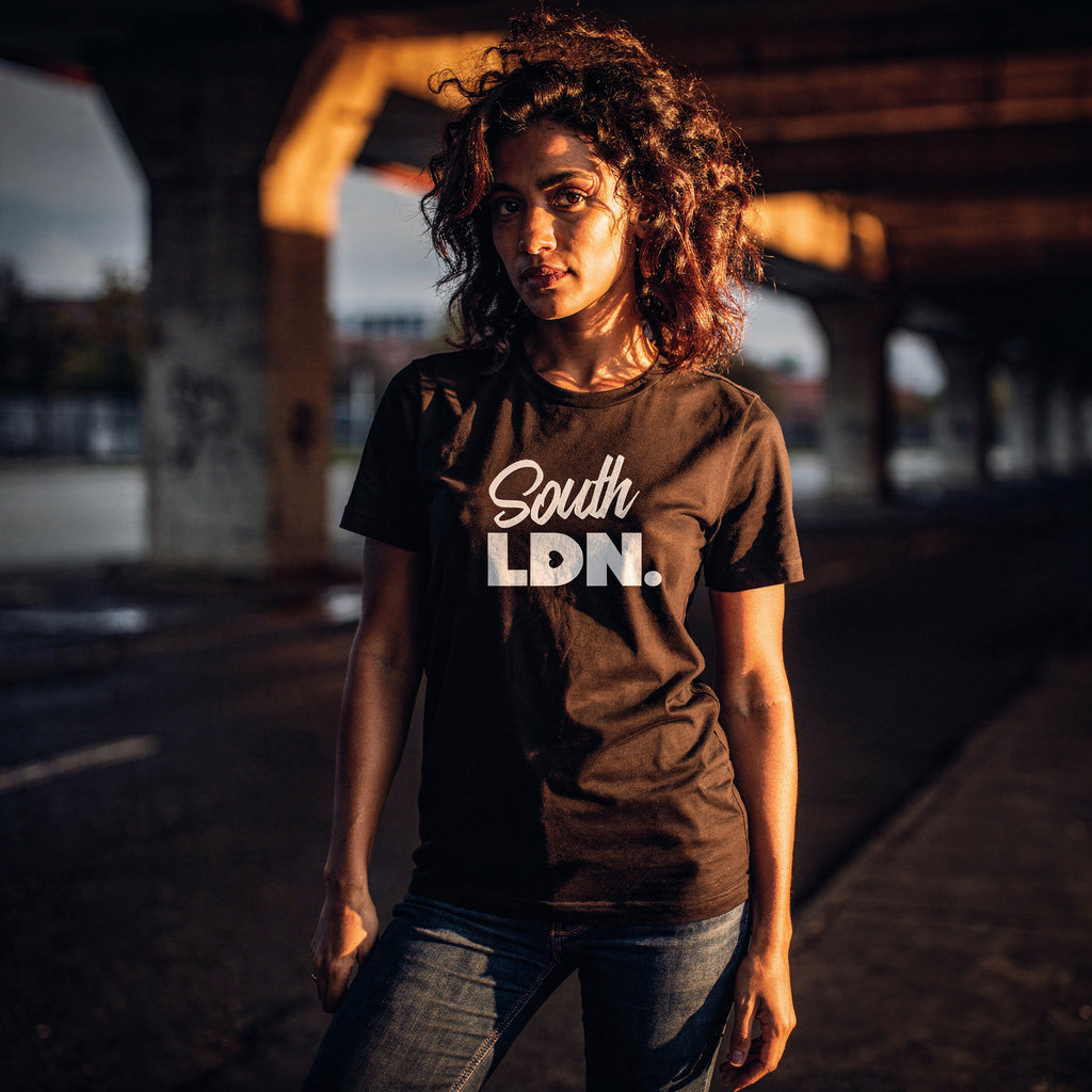 Woman wearing a 'South LDN.' t-shirt standing under a bridge.