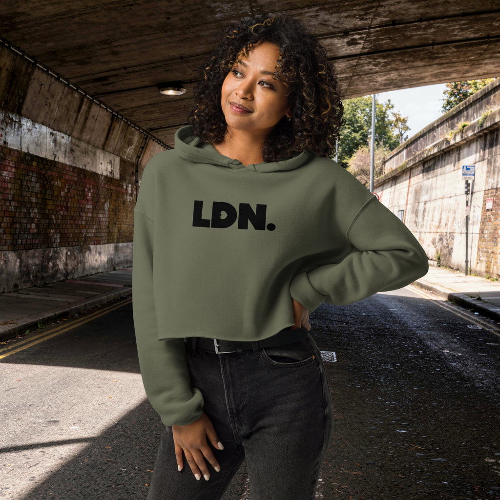 Model wearing a cropped hoodie with tonal “LDN.” graphic. Hoodie features dropped shoulders, raw hem, and dyed-to-match drawstrings. Made from cotton-poly fleece blend for soft comfort and relaxed fit. A minimal, modern streetwear piece.