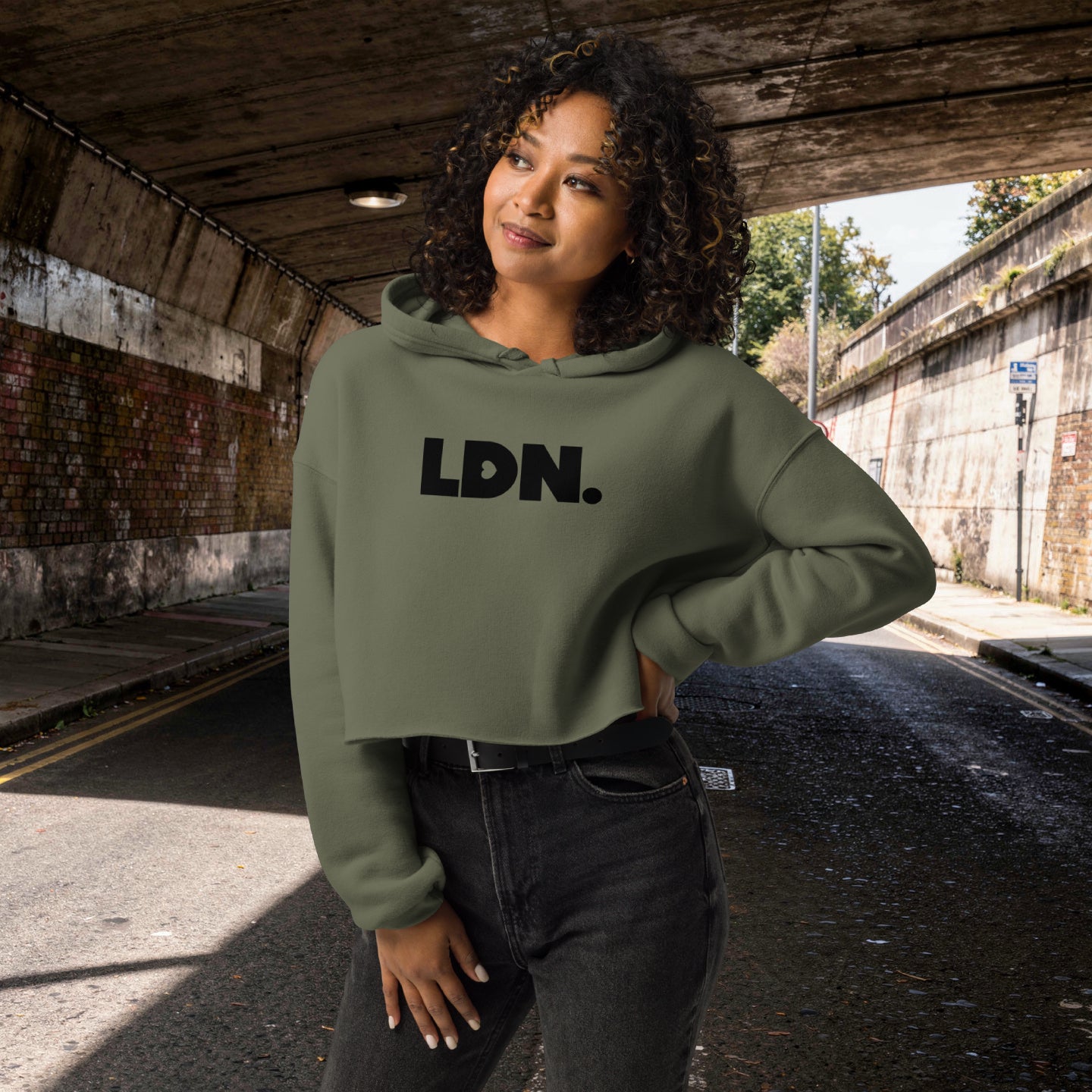 Model wearing a cropped hoodie with tonal “LDN.” graphic. Hoodie features dropped shoulders, raw hem, and dyed-to-match drawstrings. Made from cotton-poly fleece blend for soft comfort and relaxed fit. A minimal, modern streetwear piece.