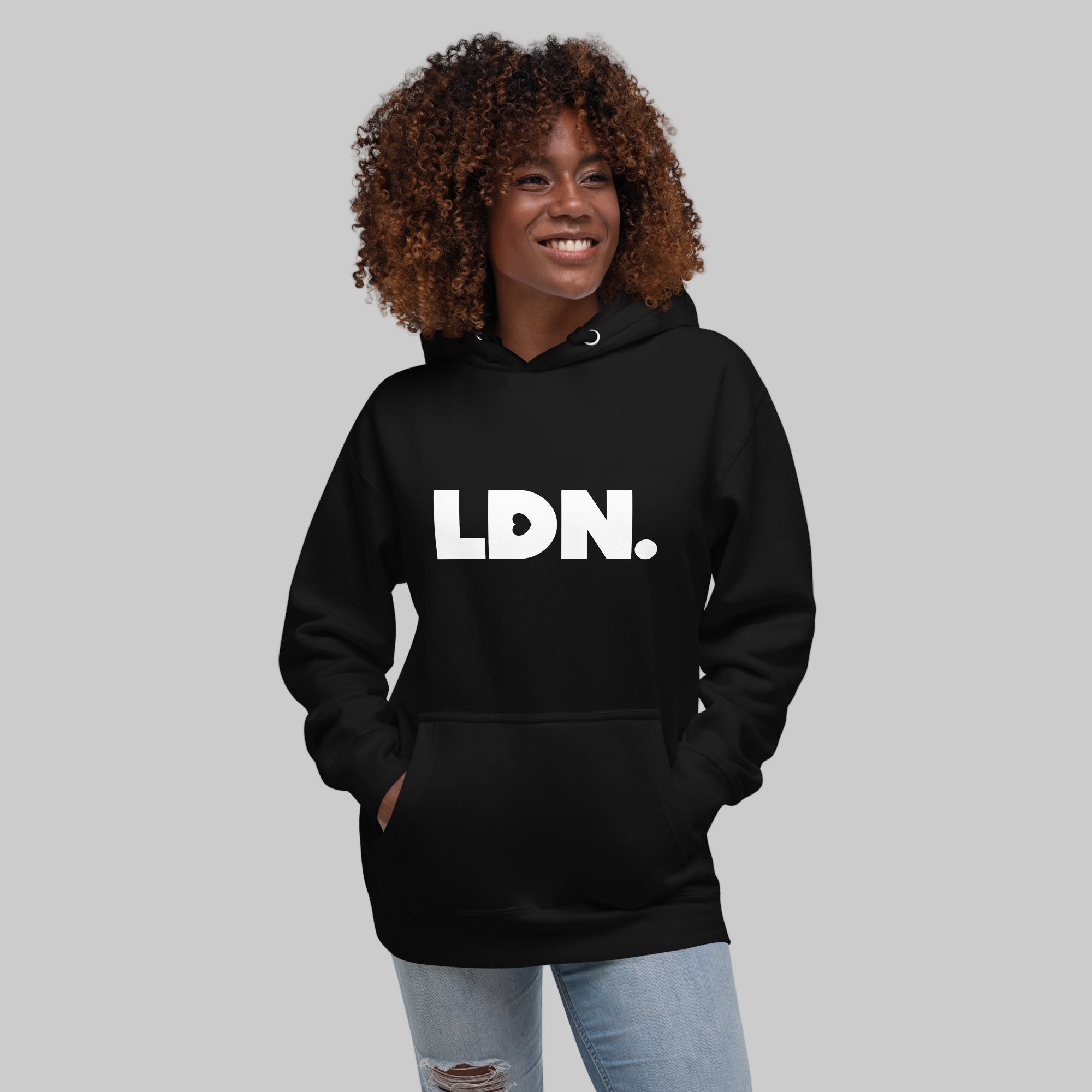 Unisex Hoodie - Black hoodie with tonal “LDN.” graphic worn by female model — soft fleece lining, relaxed streetwear silhouette, perfect for layering in cooler seasons.