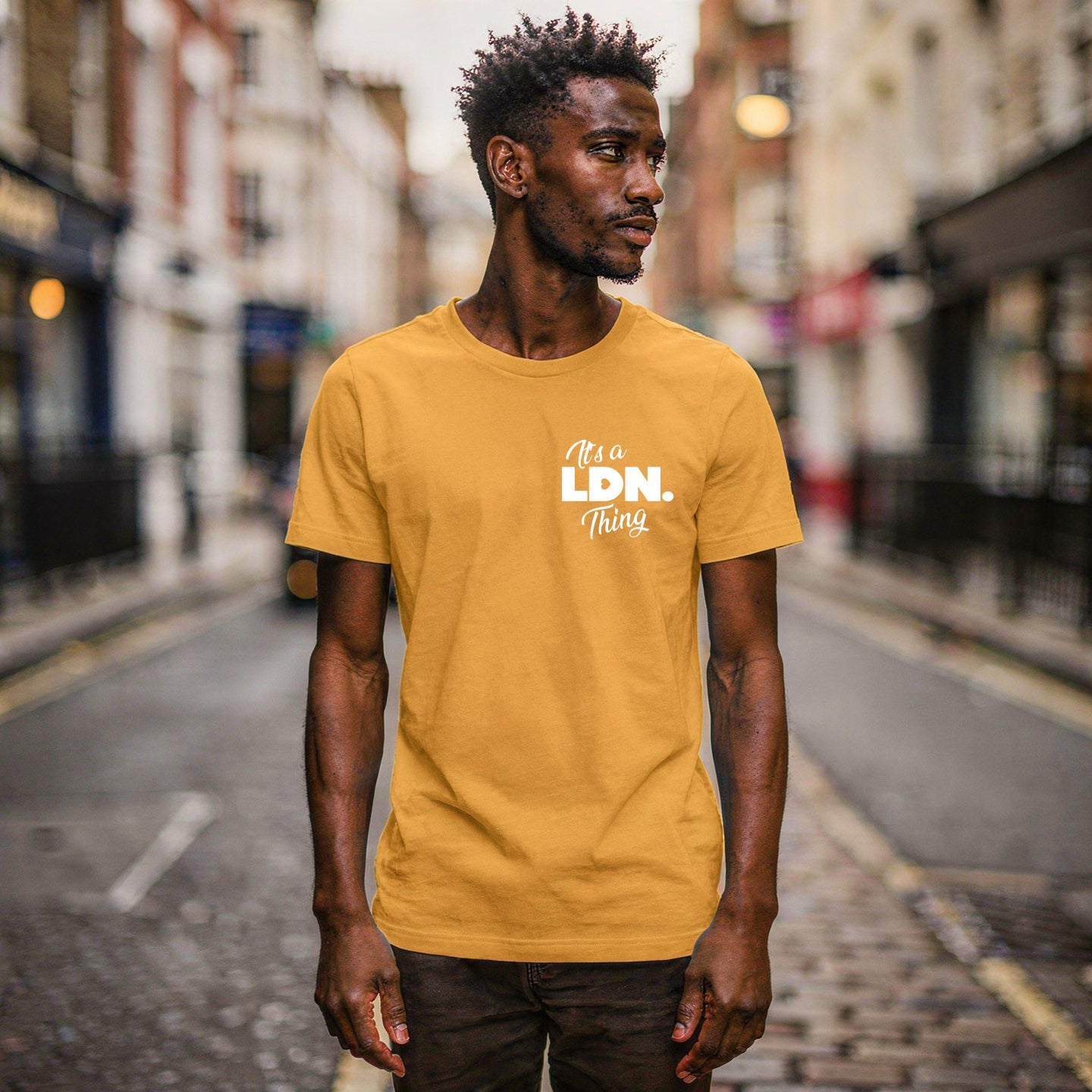 Man wearing a mustard yellow t-shirt with text on a city street