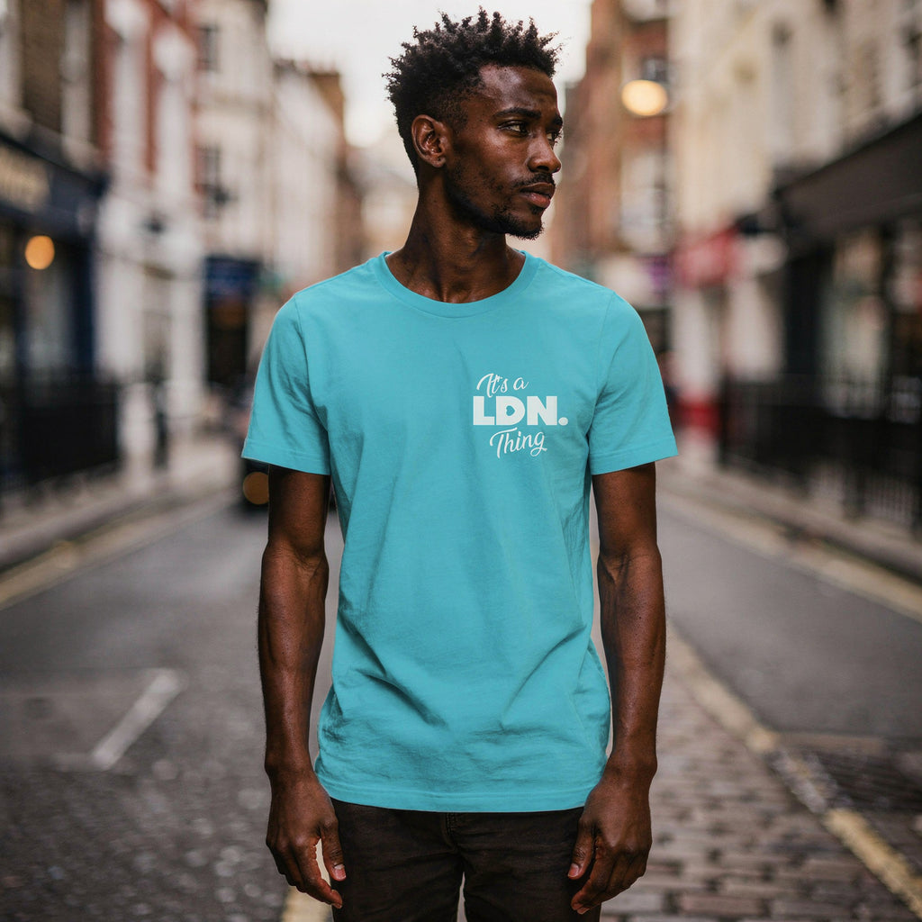 Man wearing a turquoise t-shirt with 'It's a LDN Thing' text on a city street.