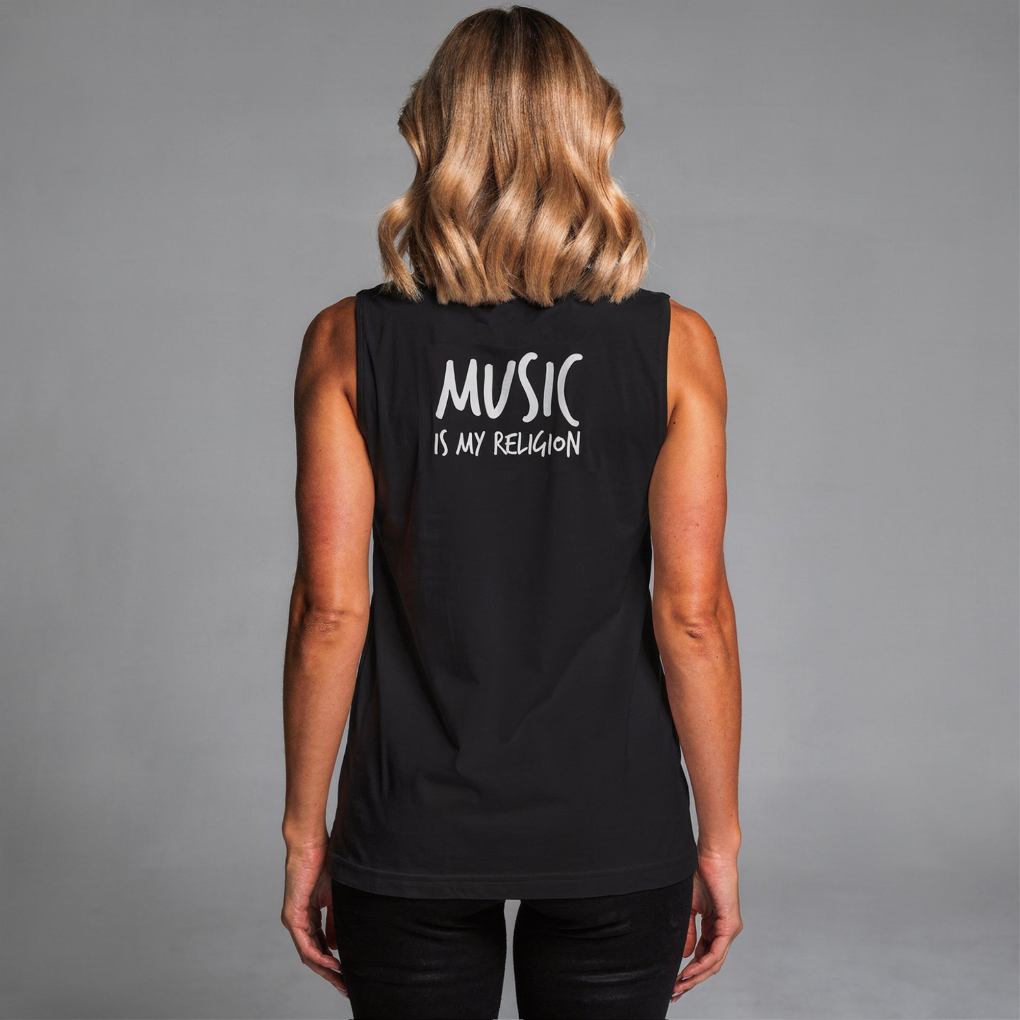 Black unisex muscle tank featuring a colourful, radiant graphic of Funky Jaysus with arms raised in a rainbow-lit robe. Relaxed fit with wide armholes, made from soft cotton. Festival-ready and music-inspired streetwear. Wording Music is my Religion.