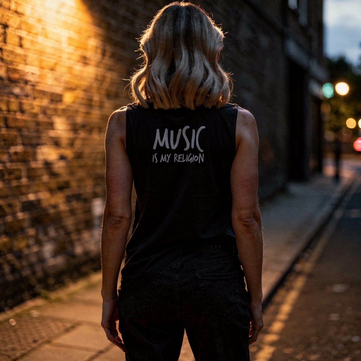 Black unisex muscle tank featuring a colourful, radiant graphic of Funky Jaysus with arms raised in a rainbow-lit robe. Relaxed fit with wide armholes, made from soft cotton. Festival-ready and music-inspired streetwear. Wording Music is my Religion.
