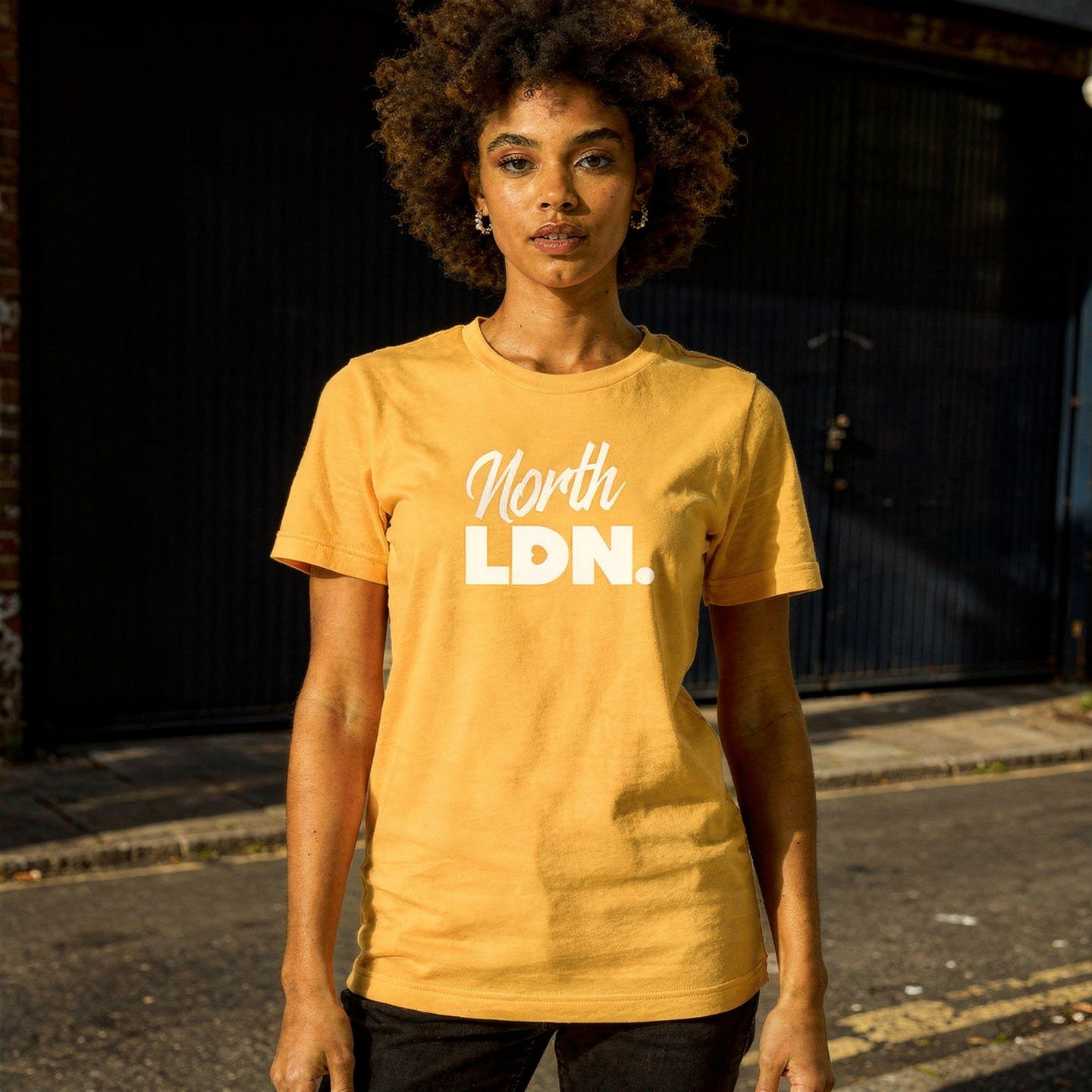 Person wearing a yellow 'North LDN' t-shirt on a street.