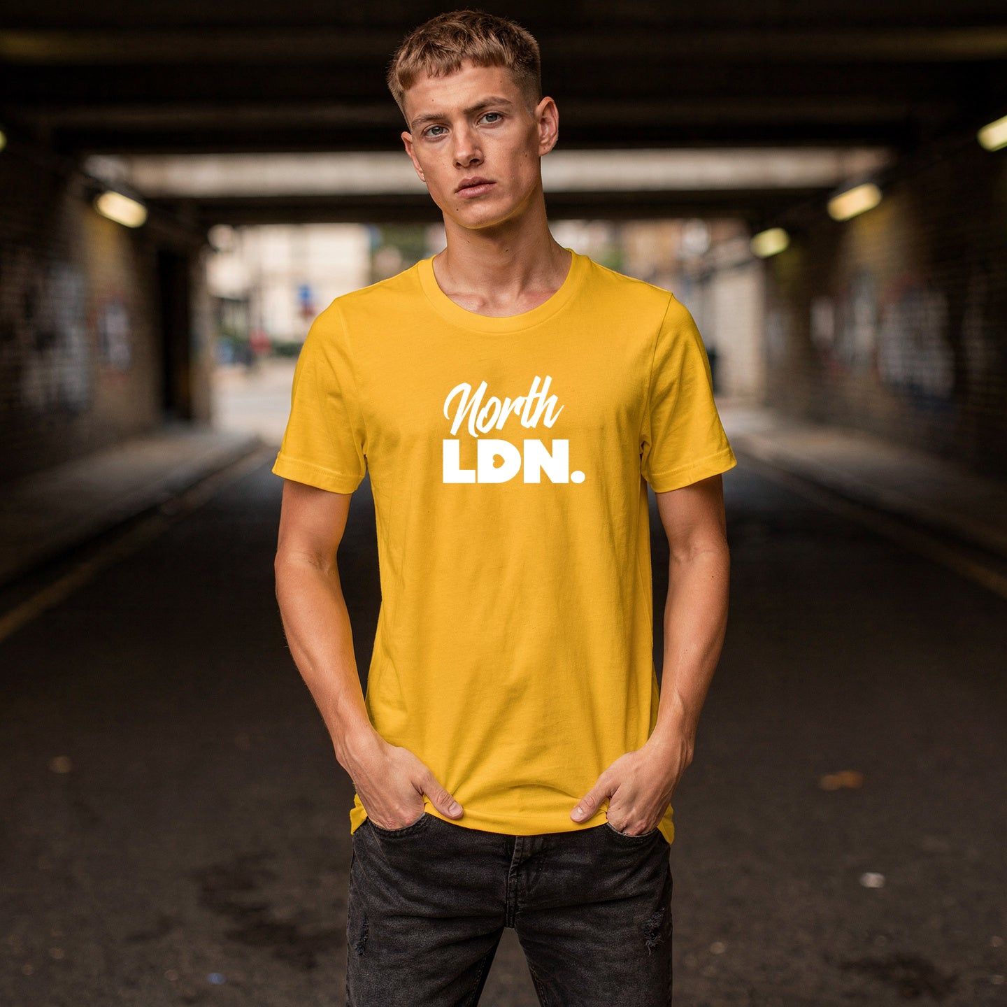 Person wearing a yellow 'North Ldn.' t-shirt standing in an urban setting.