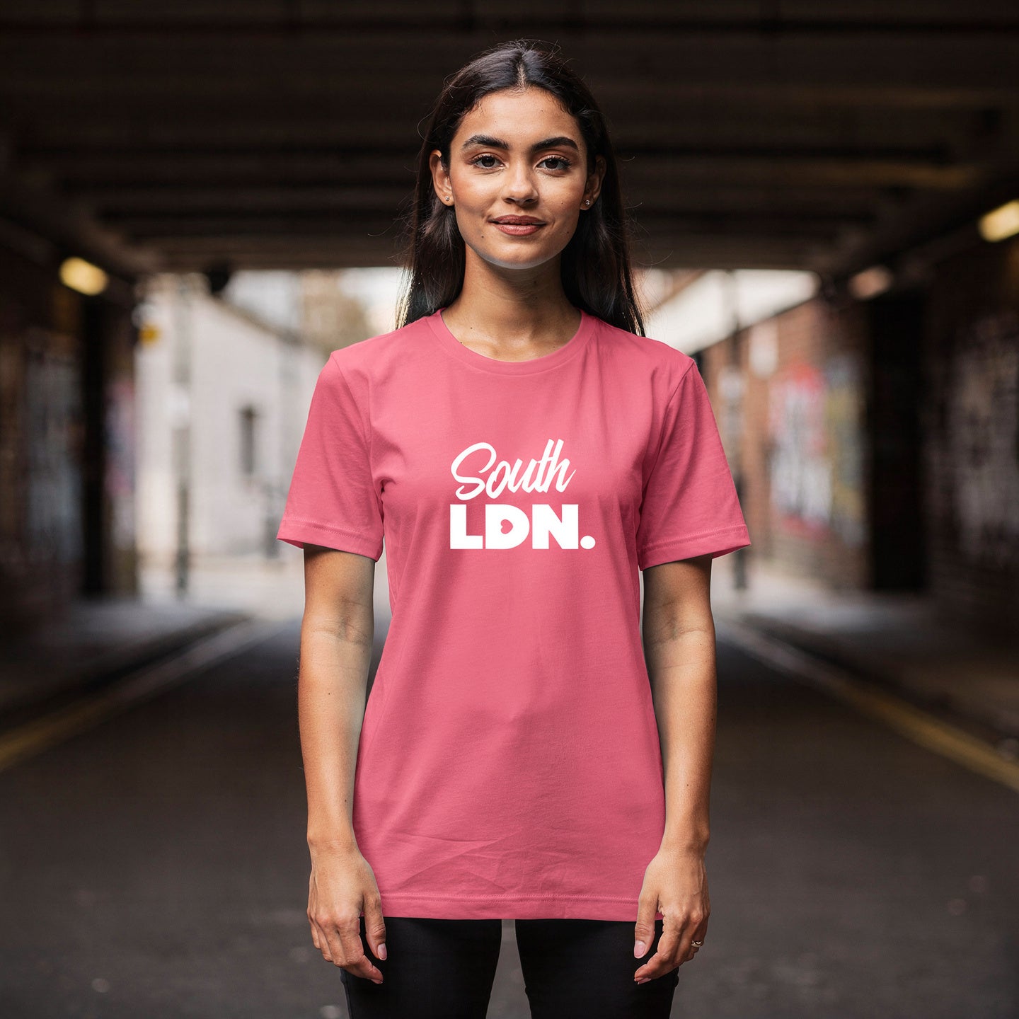 Woman wearing a pink t-shirt with 'South LDN.' text in an urban setting