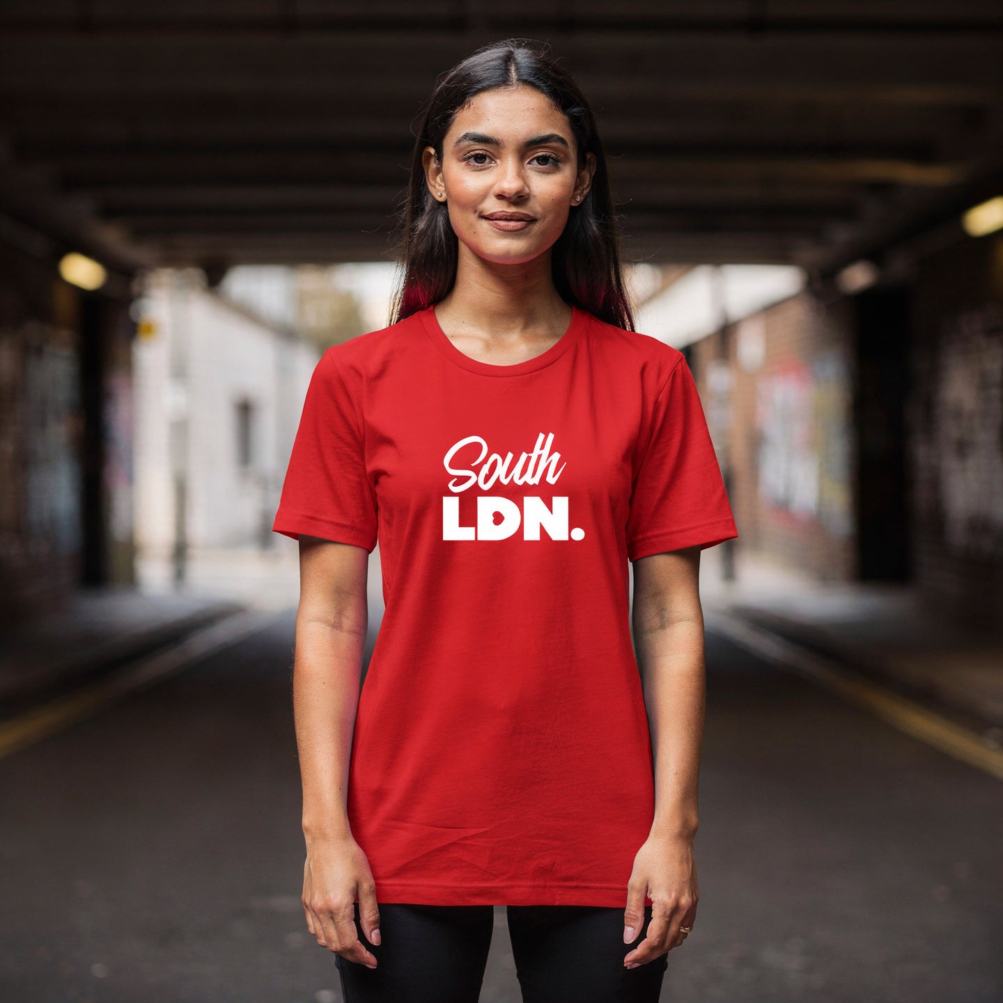 Woman wearing a red 'South LDN.' t-shirt standing in an urban setting.