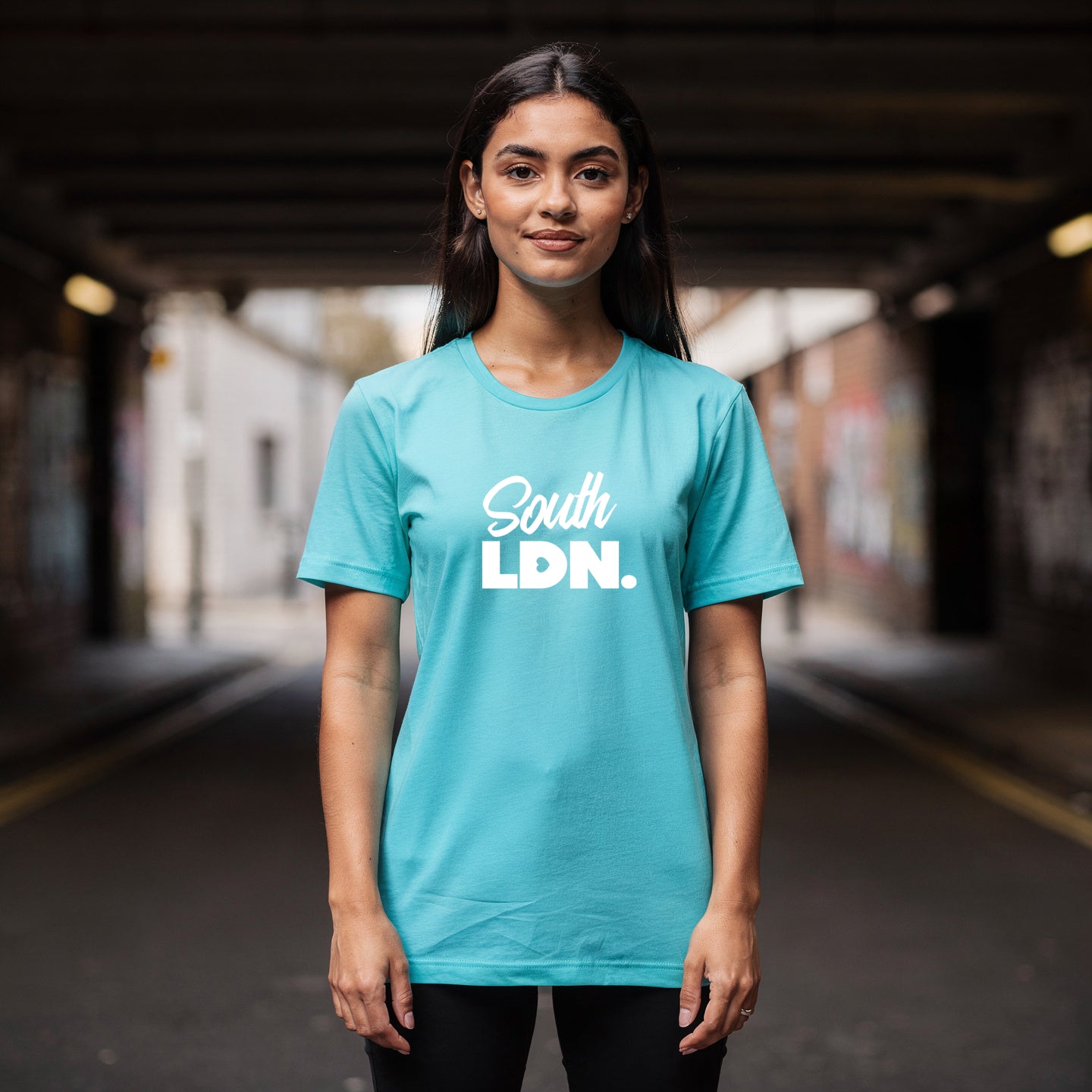Woman wearing a turquoise t-shirt with 'South LDN.' text in an urban setting