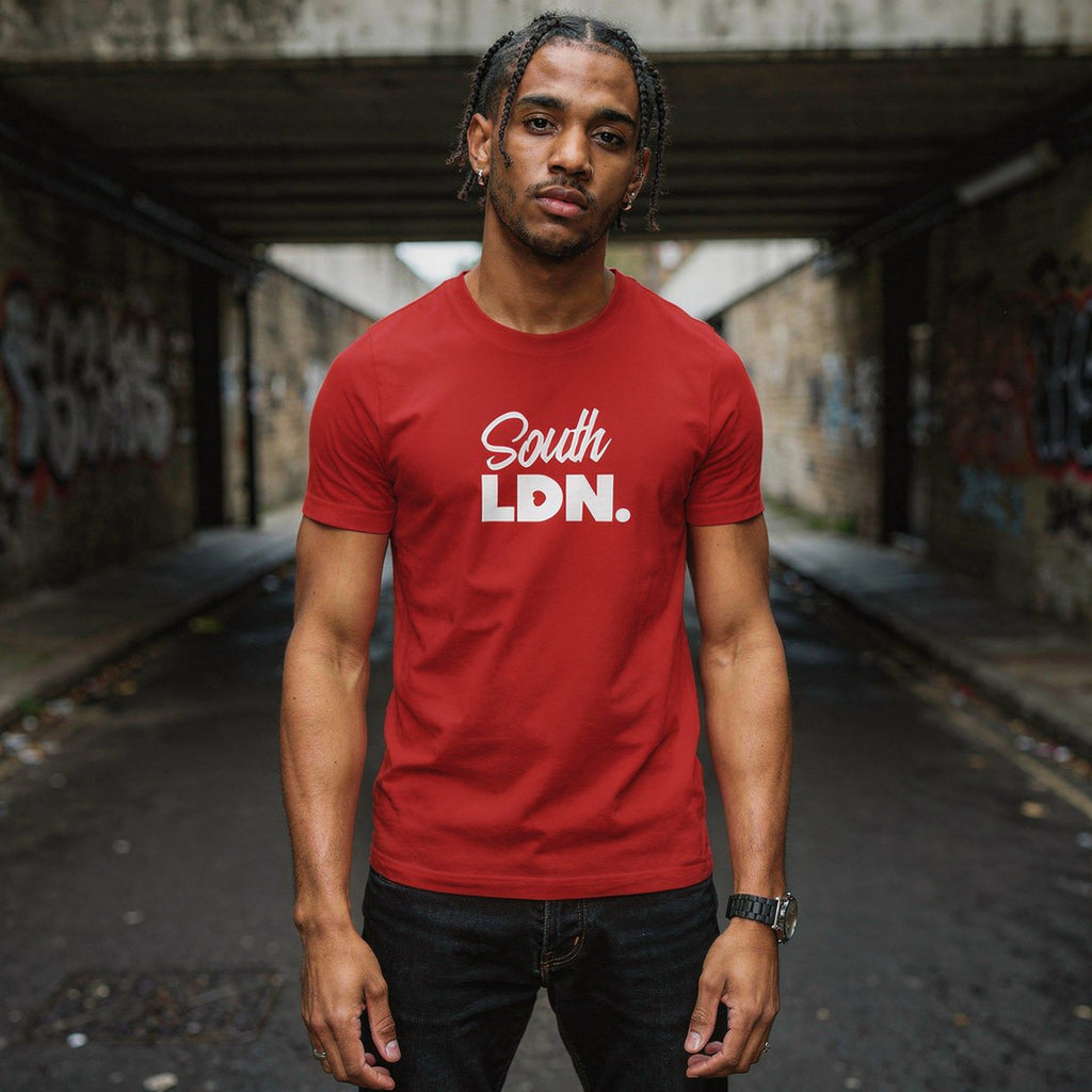 Man wearing a red 'South LDN.' t-shirt standing in an urban alleyway.