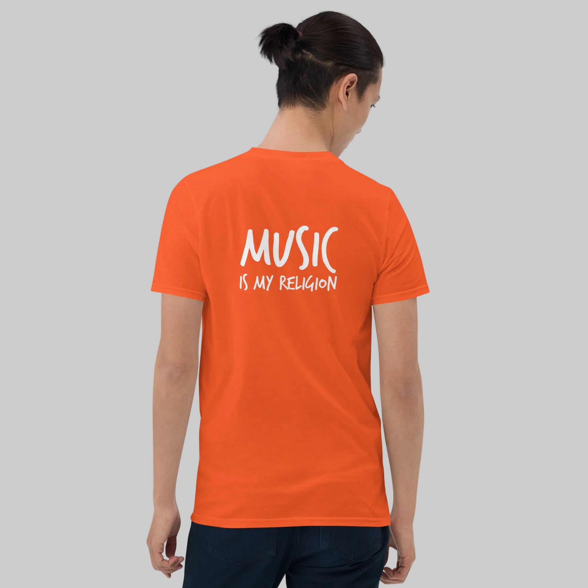 Person wearing an orange t-shirt with 'MUSIC IS MY RELIGION' text on the back, standing against a white background.