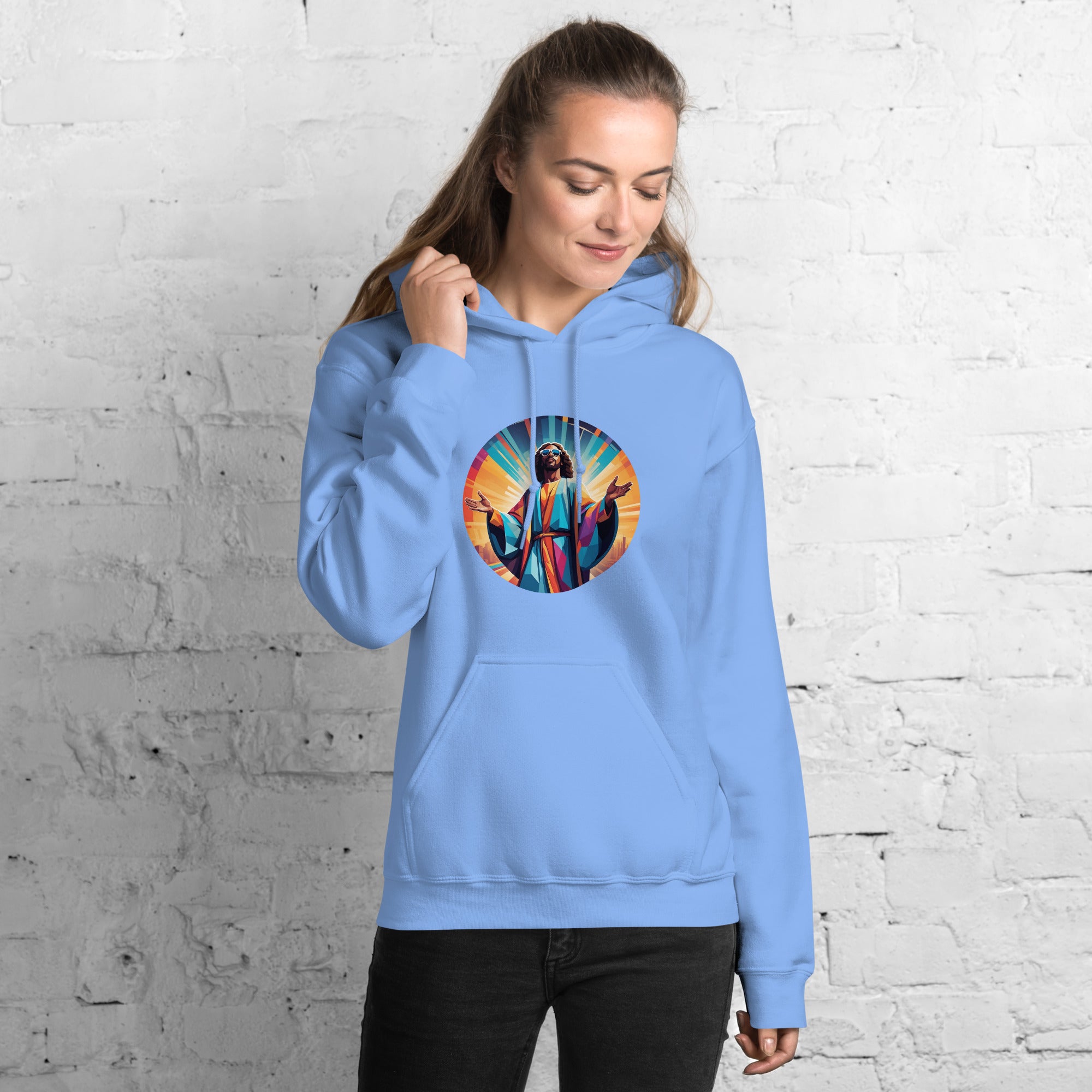 Person wearing a light blue hoodie with a colorful graphic design against a white brick wall.