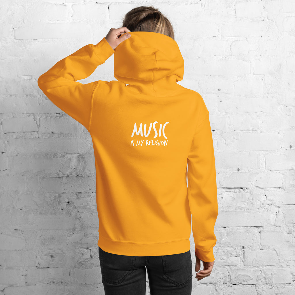 Person wearing a yellow hoodie with 'Music is my Religion' text on the back against a white brick wall.