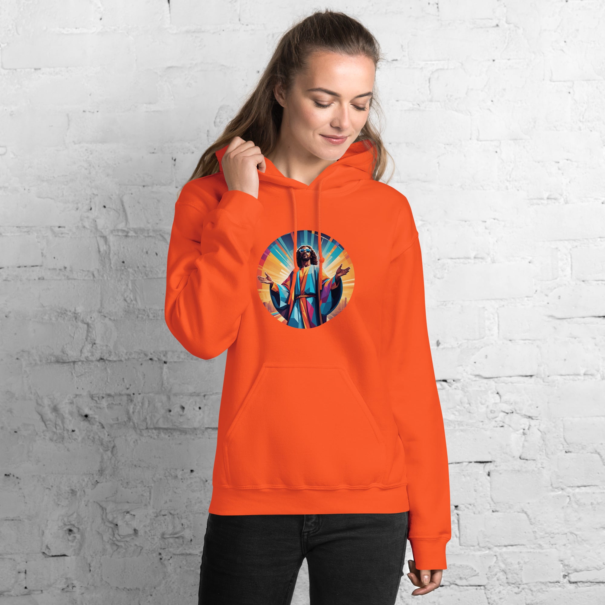 Person wearing an orange hoodie with a colorful graphic design against a white brick wall.