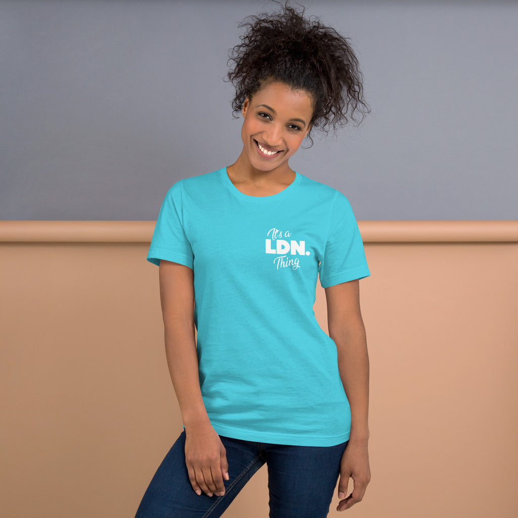 Woman wearing a turquoise t-shirt with 'LDN' text, standing against a plain background