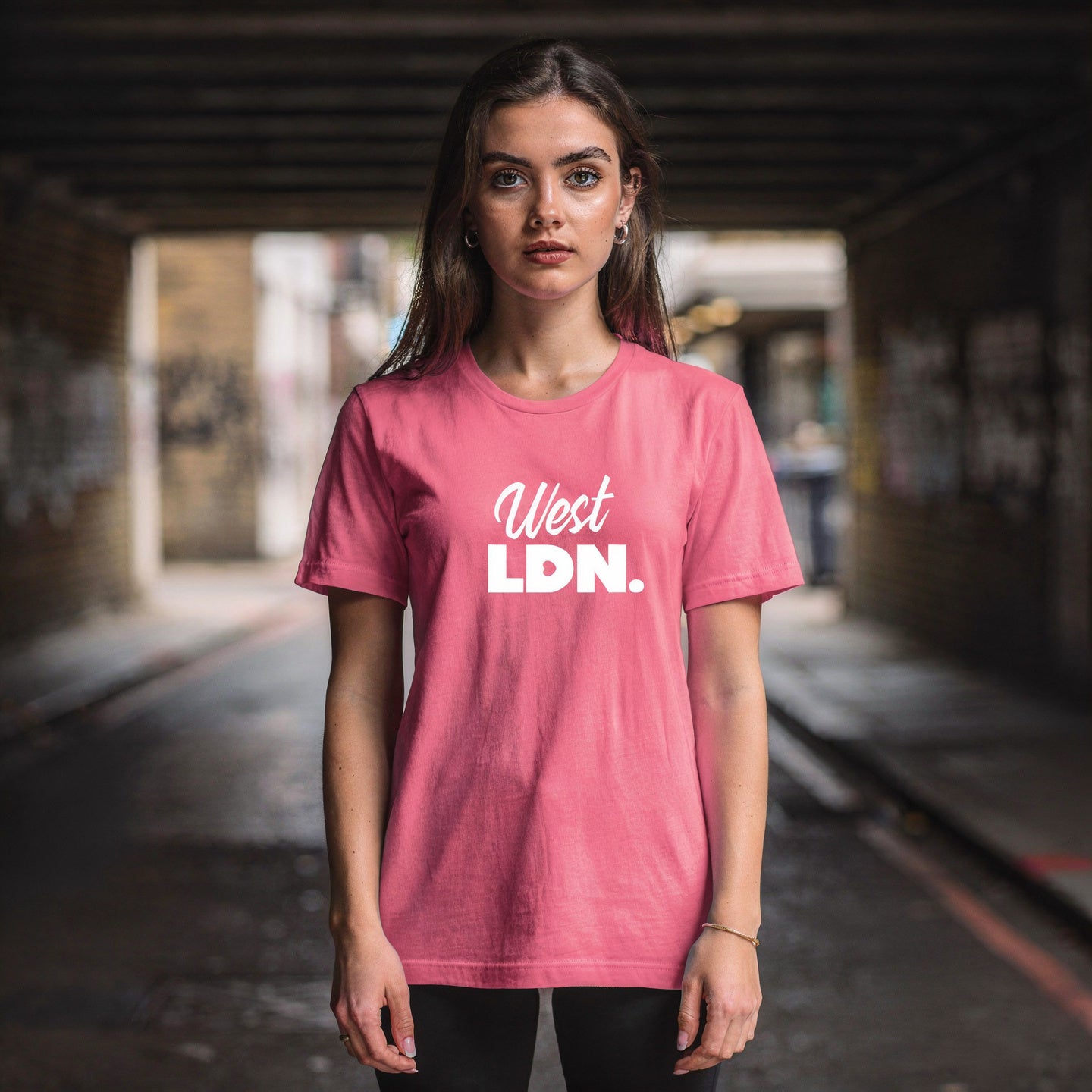 Model wearing a t-shirt with 'West LDN' text, standing in an urban London underpass
