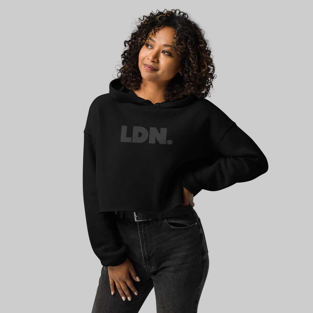 Model wearing a cropped hoodie with tonal “LDN.” graphic. Hoodie features dropped shoulders, raw hem, and dyed-to-match drawstrings. Made from cotton-poly fleece blend for soft comfort and relaxed fit. A minimal, modern streetwear piece.