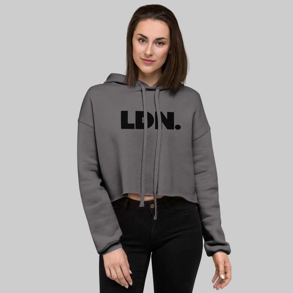 Model wearing a cropped hoodie with tonal “LDN.” graphic. Hoodie features dropped shoulders, raw hem, and dyed-to-match drawstrings. Made from cotton-poly fleece blend for soft comfort and relaxed fit. A minimal, modern streetwear piece.